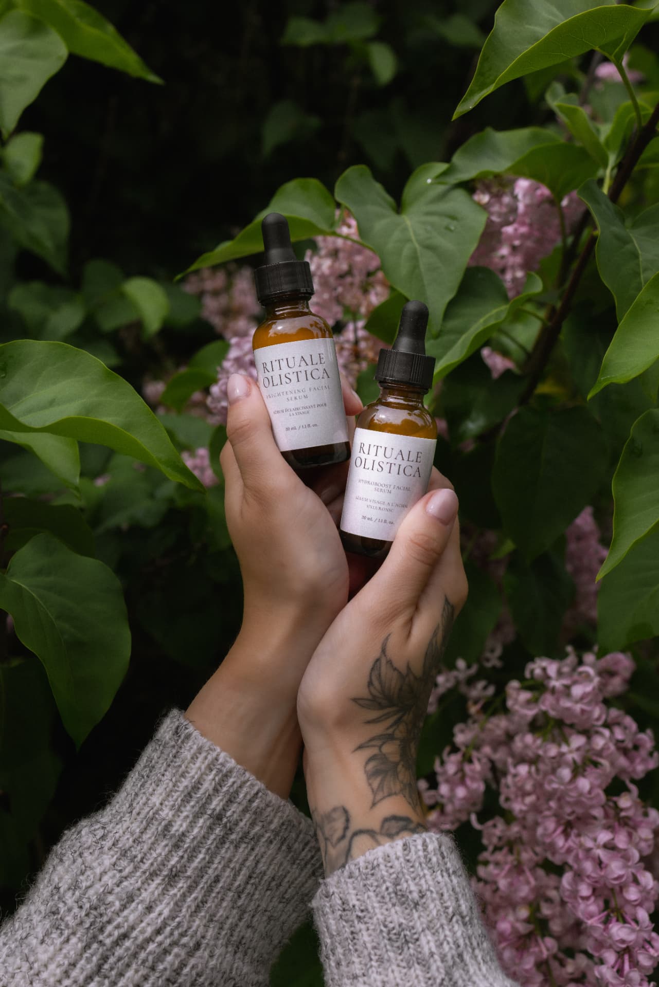 Rituale Olistica facial serums held among lilac blossoms